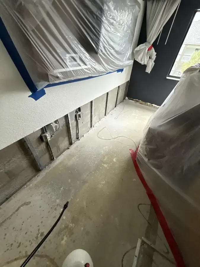 Plastic containment and flood-cut walls in a narrow room during drying