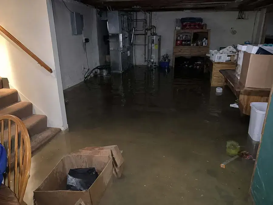 Basement flooding in Riverton, UT: standing water across the floor at the foot of the basement stairs
